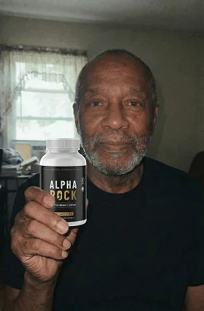 Man smiling at home holding AlphaRock capsules